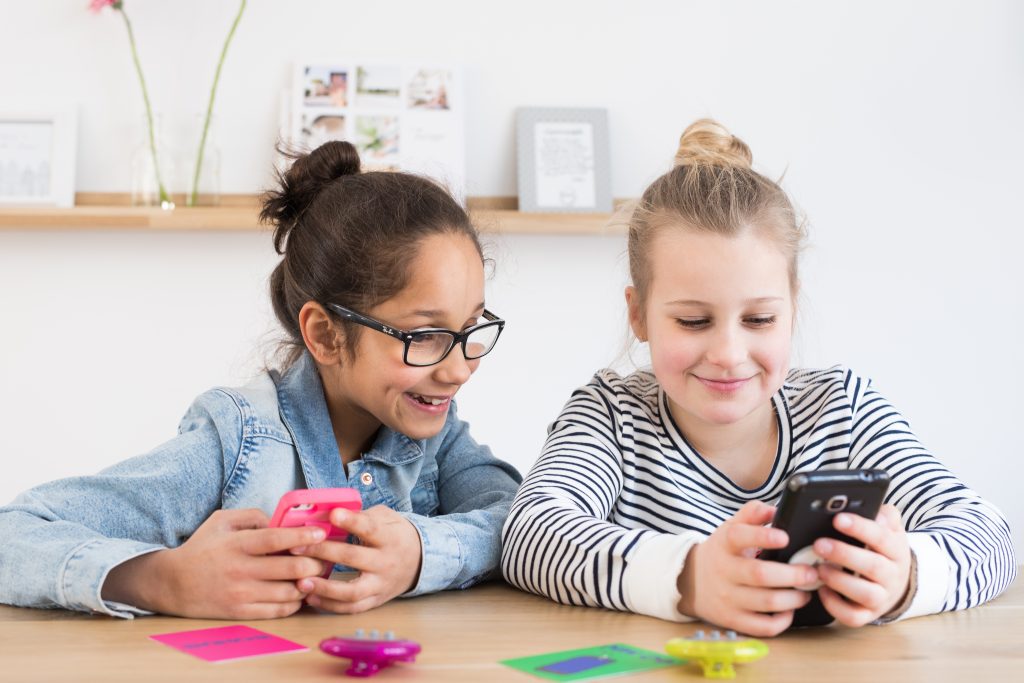 Twee meisjes met een smartphone en Mytimingcards tijdskaarten op tafel