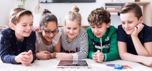 Fünf Kinder schauen gemeinsam auf ein Tablet
