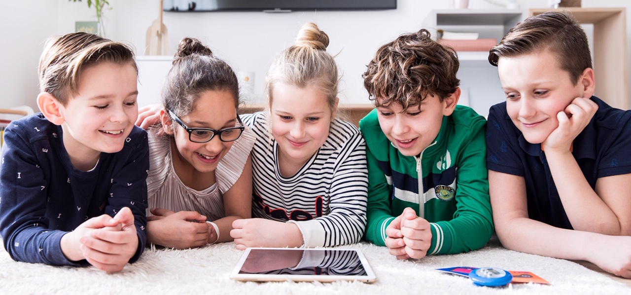 Fünf Kinder schauen gemeinsam auf ein Tablet